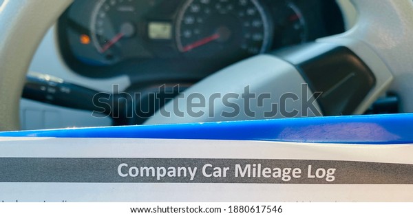 Company car mileage log papers on steering wheel of\
a car.