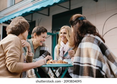 Company Caucasian senior women friendly chatting and drinking coffee at table in cafe terrace in summer. Female friends talking and laughing outdoor while gossiping and sipping coffe. - Powered by Shutterstock