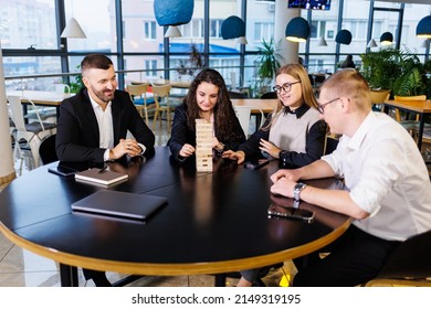 A Company Of Colleagues In The Office During A Break Plays The Board Game Jenga. Fun Board Games For Friends