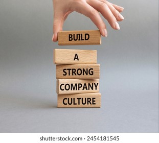 Company culture symbol. Wooden blocks with words Build a strong company culture. Beautiful grey background. Businessman hand. Business and Company culture concept. Copy space.