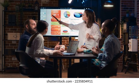 Company employee explaining analytics research results in business meeting, showing statistics data on digital board. Marketing revenue report presentation, colleagues team planning sales strategy - Powered by Shutterstock