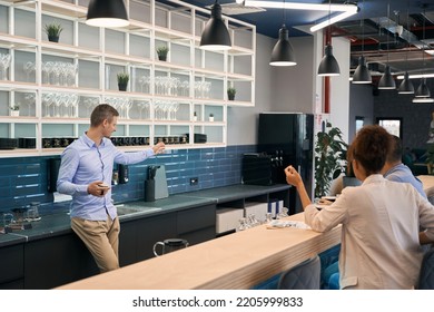 Company employee and his coworkers in modern office kitchen - Powered by Shutterstock