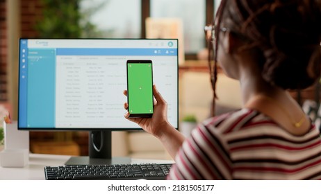 Company Employee Looking At Smartphone Display With Greenscreen, Doing Remote Job At Home. Using Isolated Chroma Key Copyspace With Blank Mockup Template And Mobile Phone Background.