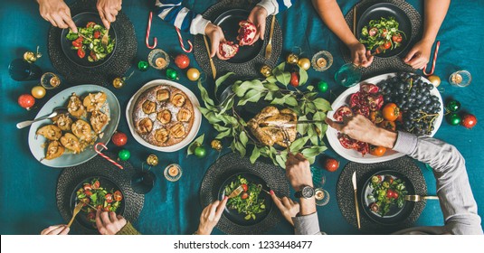 Company Of Friends Of Different Ages Gathering For Christmas Or New Year Party Dinner At Festive Table. Flat-lay Of Human Hands Eating Meals And Celebrating Holiday, Top View