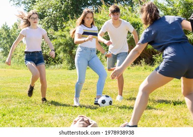 Company Of Glad Teenagers Playing Football In Park