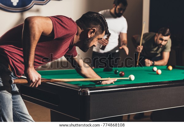 company of handsome men\
playing in pool 