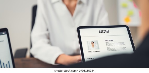 Company Human Resource (HR) is holding a resume application on tablet in hand. Young Asian woman talking to give job interviews. - Powered by Shutterstock