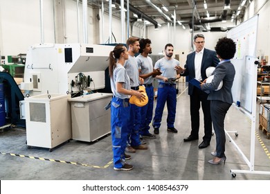 Company Manager Talking With Group Of Industrial Workers While Having Staff Meeting In A Factory. 