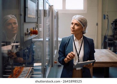 Company manager using touchpad while monitoring the processing machine in factory plant..