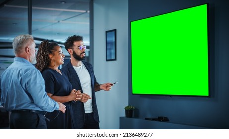 Company Operations Manager Holds Meeting Presentation for a Team of Executives. Adult Male Uses Wide TV Set with Horizontal Green Screen Mock Up Display. People Work in Business Office. - Powered by Shutterstock