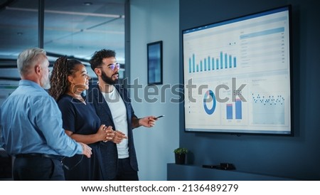 Company Operations Manager Holds Meeting Presentation. Diverse Team Uses TV Screen with Growth Analysis, Charts, Statistics and Data. People Work in Business Office. Foto stock © 