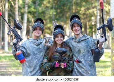 Company of three smiling paintball players posing outdoors