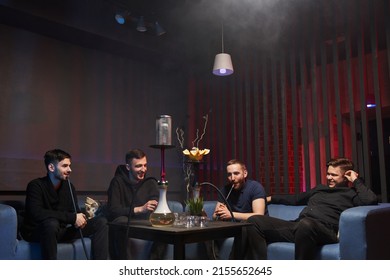 a company of young men smokes a hookah in an atmospheric cafe with a hookah