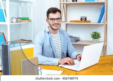 IT Company. Young Programmer Working With Laptop. Nice Office Interier. Professional Coder Looking At Camera And Smiling