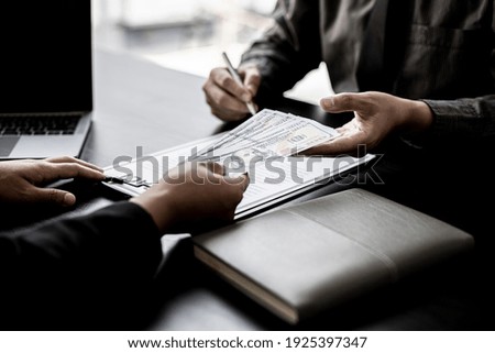 The company's procurement manager is contracting a partner company, accepting large amounts of bribes in dollar bills to cooperate in defrauding the company, fraud is illegal and immoral.