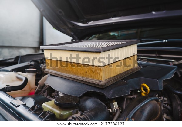 Comparing new and used car air filters placed on\
the engine