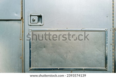The compartment door on the side of a silver metallic horse trailer