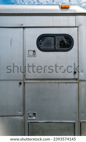 The compartment doors on the side of a silver metallic horse trailer