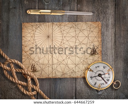 Compass, divider, rope and map on old wood desk. Exploration and nautical theme grunge background