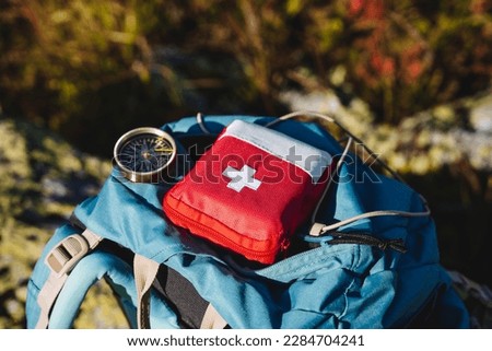 Compass first aid kit are in a backpack, a navigator in the taiga, a first aid kit in emergency situations, a white cross, medicines in a red bag. High quality photo