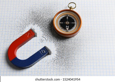 Compass and magnet with iron powder on squared paper