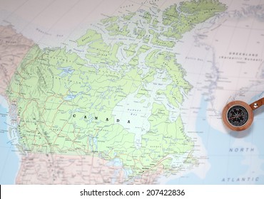 Compass on a map pointing at Canada and planning a travel destination