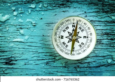 compass on old wood table with water drops, find the right direction concept, flat top view