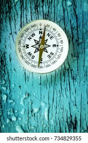 compass on old wood table with water drops, find the right direction concept, flat top view