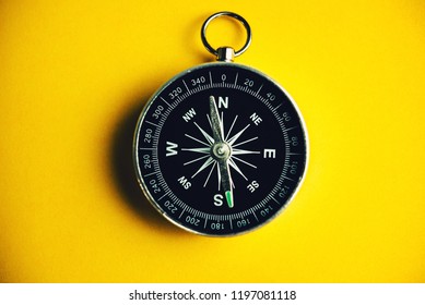 Compass on yellow background, minimal-travel-concept.