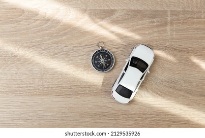 Compass With Toy Car Model On Wooden Table. Travel Concept