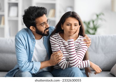 Compassionate eastern husband giving comfort, support to upset wife, holding shoulders, speaking expressing empathy. Man feeling guilty, asking girlfriend to forgive. Relationship, compassion concept