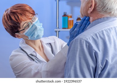 Compassionate Female Doctor In White Coat And Mask Put Her Gloved Hands On The Neck Of Senior Male Patient. Professional Medical Care In The Hospital.