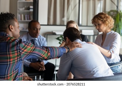 Compassionate Young Diverse Business People Supporting Depressed Male Colleague At Group Psychotherapy Meeting. Stressed Unhappy Young Man Sharing Complaints Or Life Problems With Teammates.