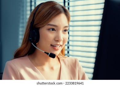 Competent female operator working on computer and while talking with clients. Concept relevant to both call centers and customer service offices. - Shutterstock ID 2233819641