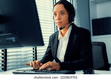 Competent female operator working on computer and talking with clients. Concept relevant to both call centers and customer service offices. - Shutterstock ID 2233819701