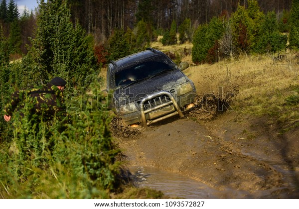 Competition, energy and motorsport concept.\
Car racing in autumn forest. Off road vehicle or SUV overcomes\
obstacles. Auto racing on fall nature\
background