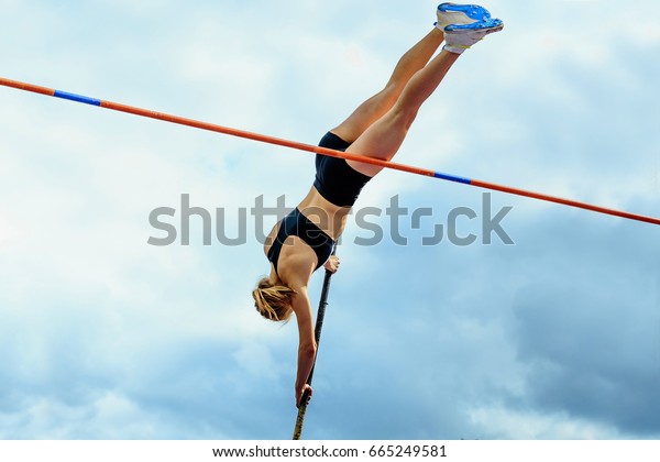 competition pole vault jumper female on blue\
sky background