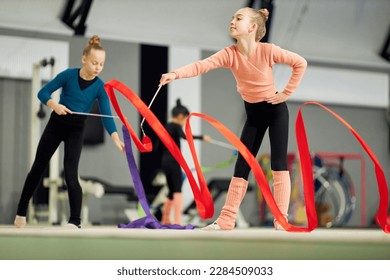 Competition preparation. Little girl, child, rhythmic gymnast training indoor, doing exercise with ribbon. Concept of sportive lifestyle, childhood, education, health, professional sport, championship - Powered by Shutterstock