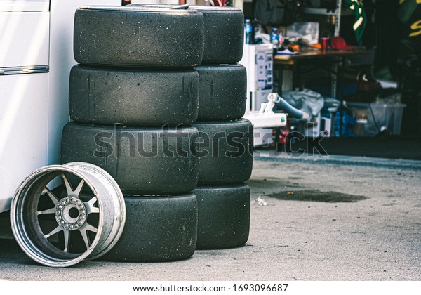 competition\
tires stacked in the pits. Racing\
workshop