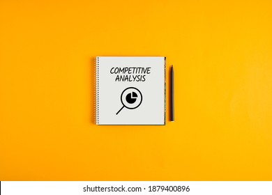 Competitive analysis written on a notepad with black pen next to it against yellow background. Competitor analysis in marketing business concept.