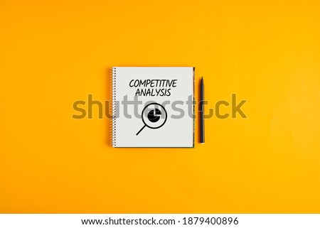 Competitive analysis written on a notepad with black pen next to it against yellow background. Competitor analysis in marketing business concept.