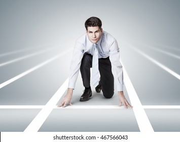 Competitive businessman at starting position. Businessman posing like he is ready to run in a race - Powered by Shutterstock