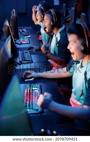 Competitive gamers playing and winning in online video game on high-powered game computers in cyber club