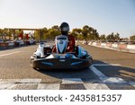 Competitive man racing in go-carts at finish of motor race track