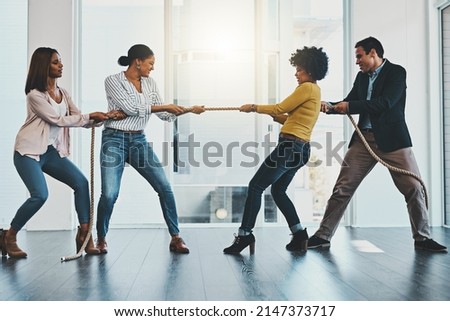 Its a competitive market out there with many challenges. Shot of a group of businesspeople pulling on a rope during tug of war in an office.