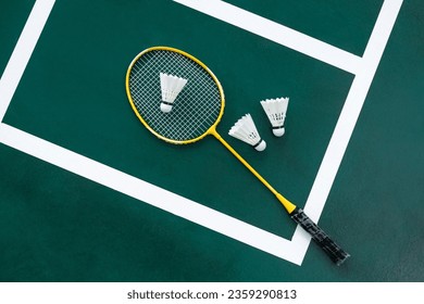 Competitive sports conceptual idea with badminton rackets and shuttlecock on green badminton court