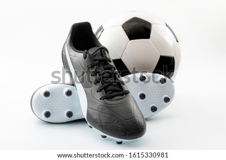 Competitive team sports, active life hobbies and athletic gear concept with old-fashioned black leather football cleats or athletics boots with laces and soccer ball isolated on white background