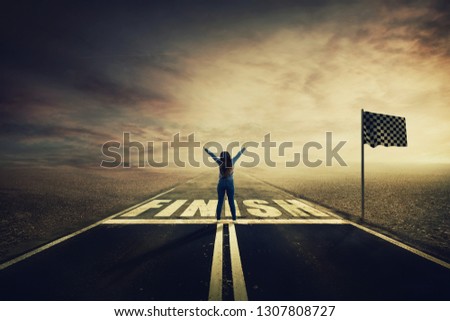 Competitive young woman on the road celebrate culmination raising hands up crossing the finish line. Surreal challenge winning concept, motivation and success. Opportunity way for self development.