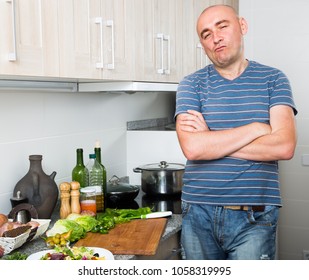 Complacent Positive Guy Stands Proudly In Kitchen Hands Clasped