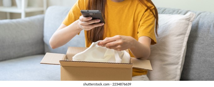 Complaint asian young woman hand using mobile phone take a photo product order from retail store after open carton box, received online shopping parcel wrong with support shop want to return package. - Shutterstock ID 2234876639